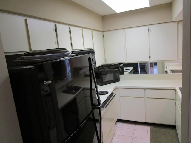 kitchen with light tile patterned floors, black appliances, and white cabinets