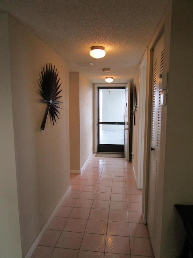 hallway featuring a textured ceiling and light tile patterned floors