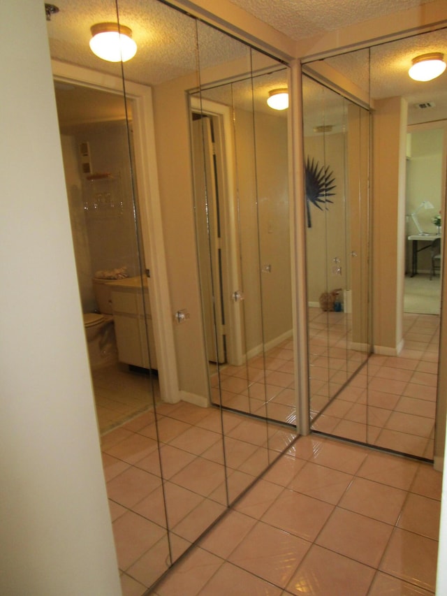 hall with a textured ceiling and light tile patterned floors