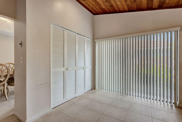 interior space featuring light tile patterned floors, wood ceiling, and baseboards