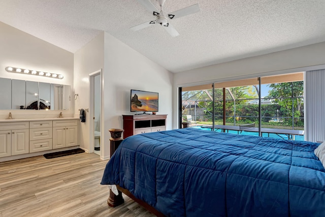 bedroom with access to exterior, light wood-style flooring, lofted ceiling, and a sink