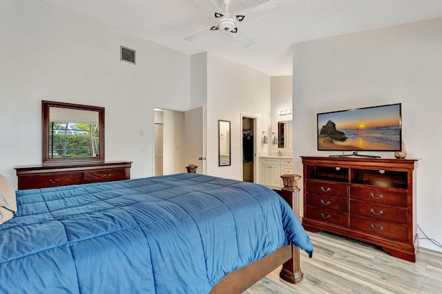 bedroom with visible vents, light wood-style flooring, a textured ceiling, connected bathroom, and ceiling fan