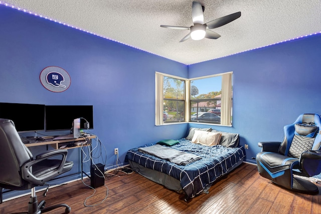 bedroom with a ceiling fan, baseboards, wood-type flooring, and a textured ceiling