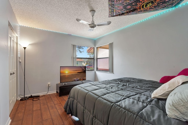 bedroom featuring ceiling fan, wood finished floors, baseboards, and a textured ceiling