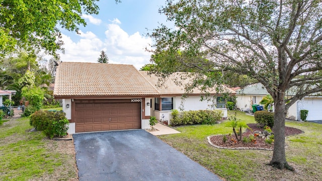 ranch-style home featuring stucco siding, a front lawn, a tile roof, aphalt driveway, and a garage