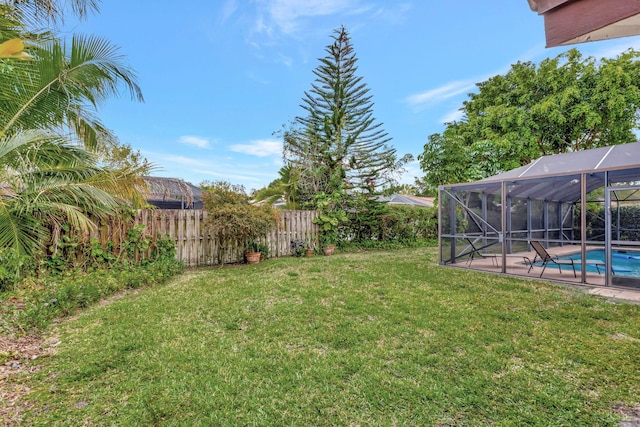 view of yard with a lanai, fence, and a fenced in pool