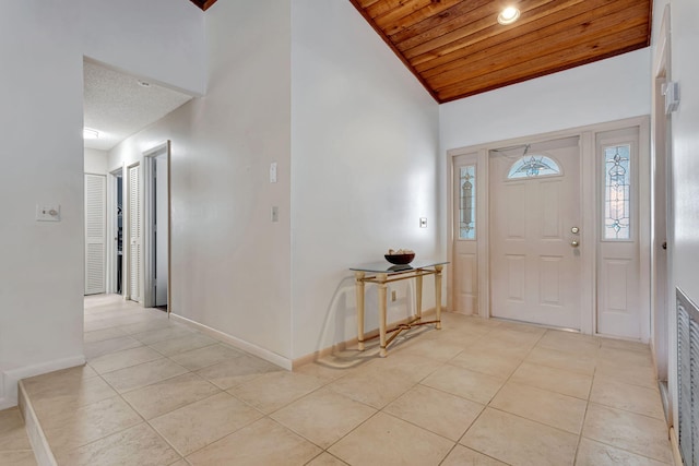 foyer with wooden ceiling, light tile patterned floors, baseboards, and high vaulted ceiling