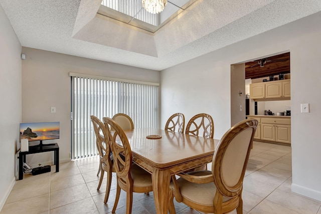 dining space featuring light tile patterned floors, a chandelier, a textured ceiling, and baseboards