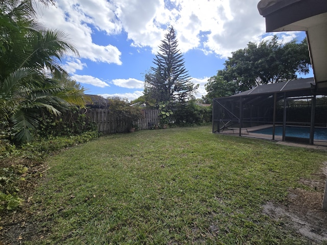 view of yard featuring a fenced in pool and glass enclosure