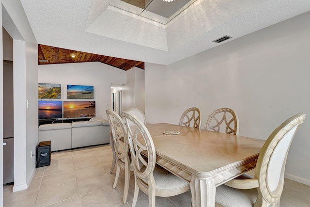 dining space with light tile patterned floors, visible vents, a textured ceiling, and vaulted ceiling
