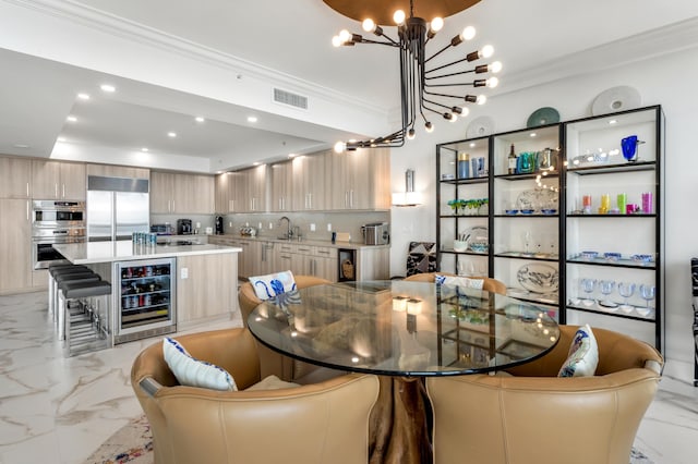 dining area with wine cooler, crown molding, sink, and a notable chandelier