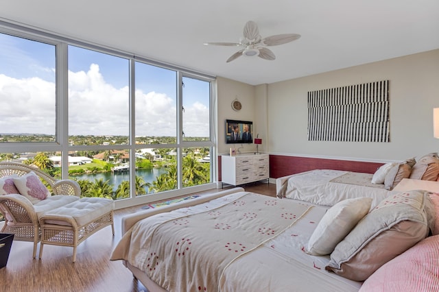 bedroom with a water view, hardwood / wood-style floors, and ceiling fan