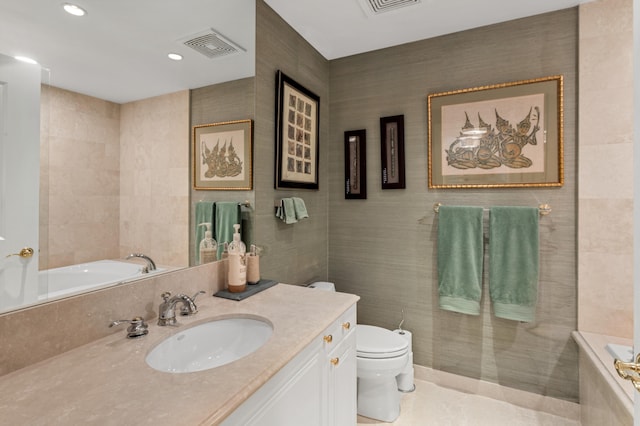 bathroom featuring tile walls, vanity, a washtub, and toilet