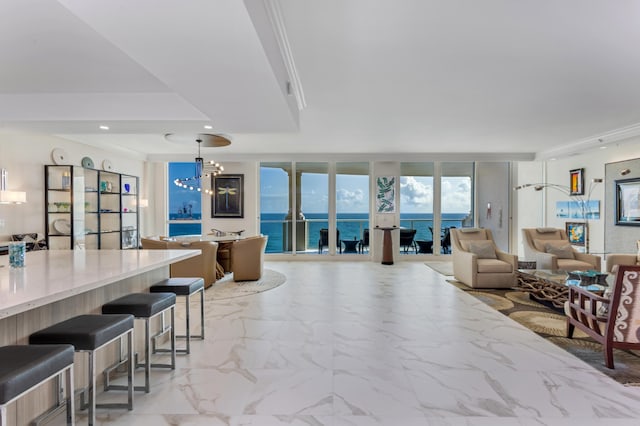 living room featuring crown molding, a water view, floor to ceiling windows, and a notable chandelier