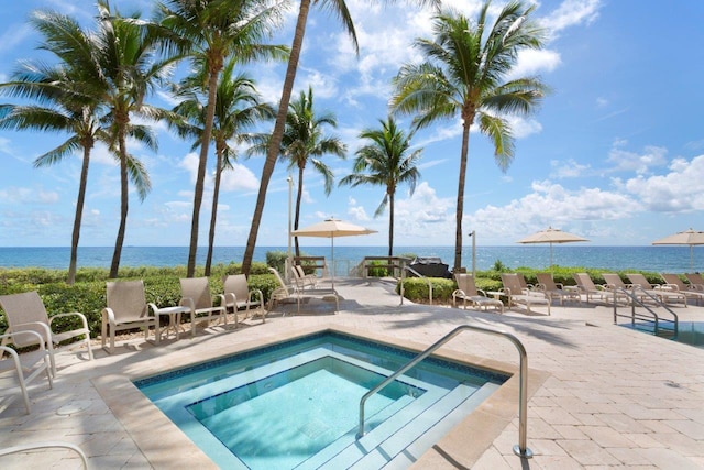 view of swimming pool featuring a hot tub, a patio, and a water view