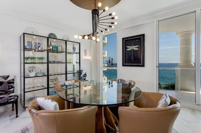 dining area featuring ornate columns, crown molding, a water view, and an inviting chandelier