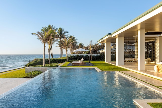 view of swimming pool with a yard, a water view, and a patio area