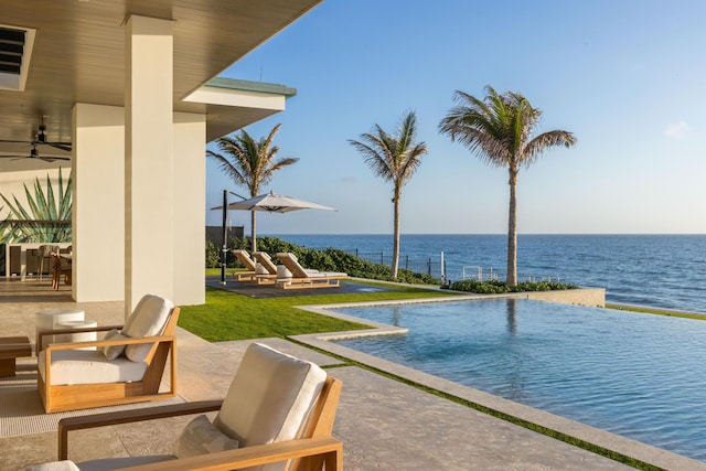 view of swimming pool with a water view, ceiling fan, and a patio area