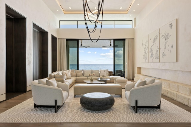 common area with ceiling fan with notable chandelier, a water view, a wealth of natural light, and wood-type flooring