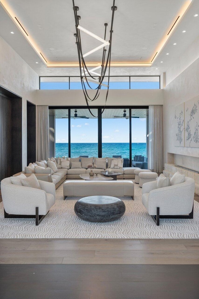 living room featuring a tray ceiling, hardwood / wood-style floors, and a water view