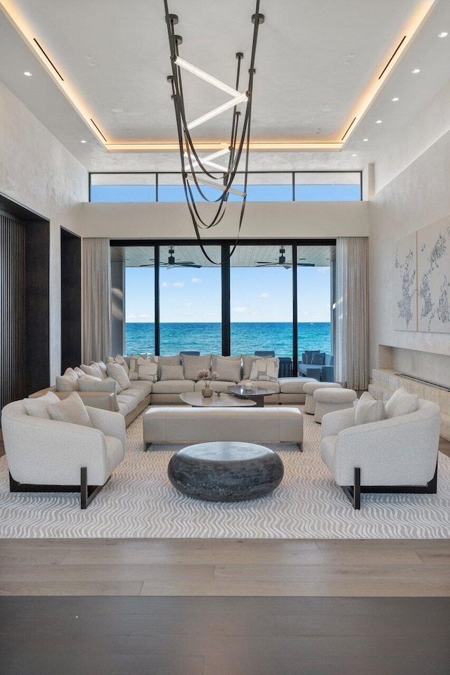 1160 S Ocean Blvd, Manalapan, FL 33462 - living area with wood finished floors, a high ceiling, a water view, plenty of natural light, and a tray ceiling