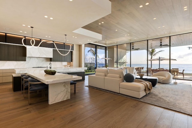 living room with a water view, wooden ceiling, wood-type flooring, and a wall of windows