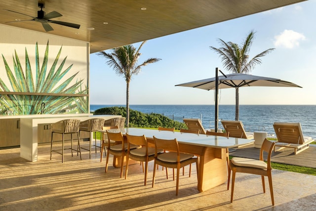 view of patio featuring a water view, exterior bar, and ceiling fan