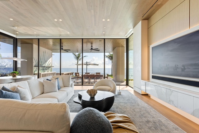 living room featuring a water view, light hardwood / wood-style flooring, ceiling fan, and floor to ceiling windows