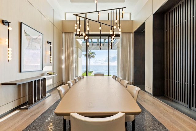 dining area featuring a water view, light hardwood / wood-style floors, and a chandelier