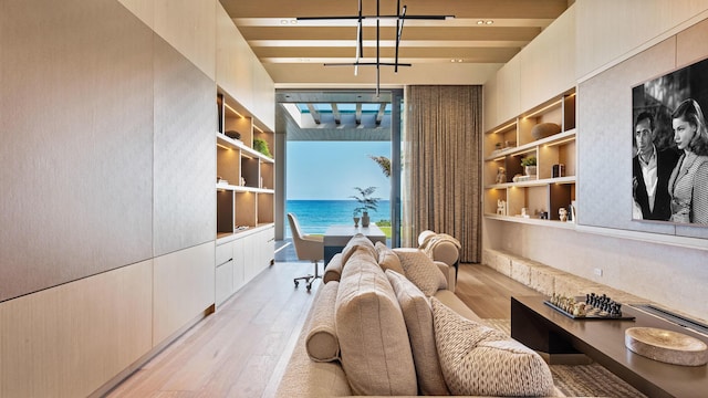 living area featuring a water view, built in features, and light hardwood / wood-style flooring