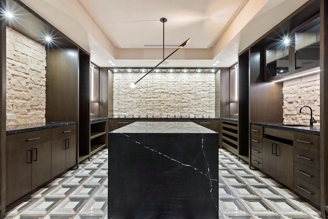 kitchen featuring sink, dark brown cabinets, a kitchen island, and decorative light fixtures