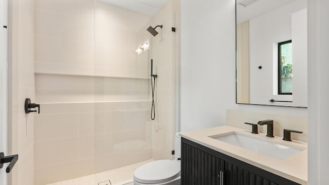 bathroom with toilet, vanity, and a tile shower