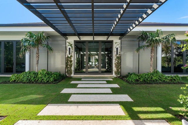 entrance to property featuring a yard, french doors, and a pergola