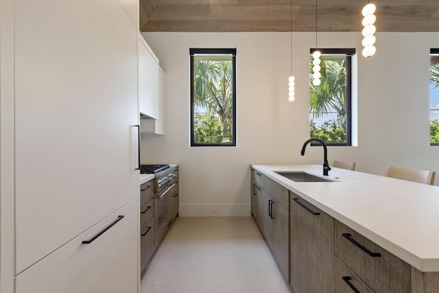 kitchen with a kitchen breakfast bar, sink, hanging light fixtures, and cooktop