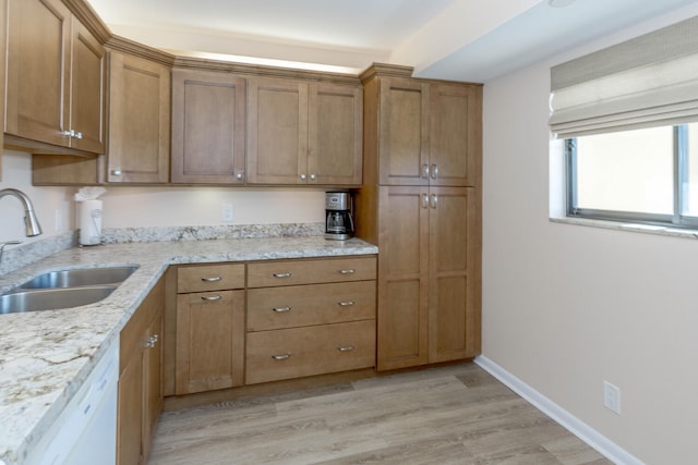 kitchen with light stone counters, sink, light hardwood / wood-style flooring, and dishwasher