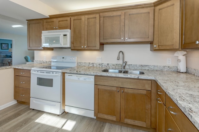 kitchen featuring white appliances, light hardwood / wood-style floors, sink, and light stone countertops