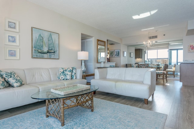 living room with a notable chandelier, hardwood / wood-style flooring, and a textured ceiling