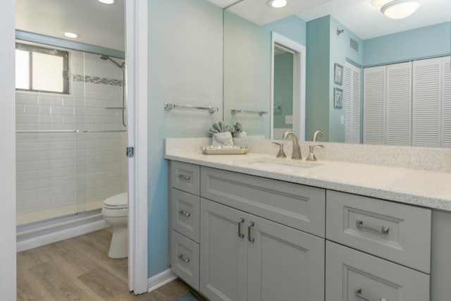 bathroom featuring an enclosed shower, hardwood / wood-style floors, vanity, and toilet