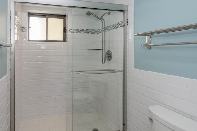 bathroom with tile walls, an enclosed shower, and toilet