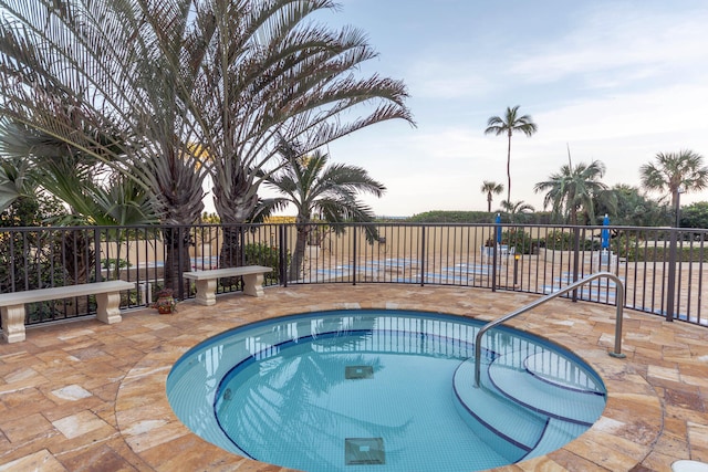 pool at dusk with a community hot tub and a patio area