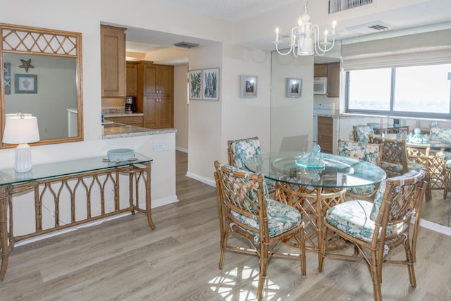 dining area with a notable chandelier and light hardwood / wood-style flooring