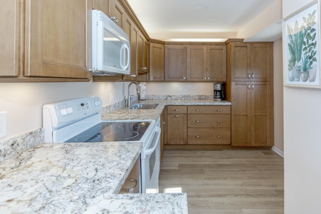 kitchen featuring light stone counters, white appliances, sink, and light wood-type flooring