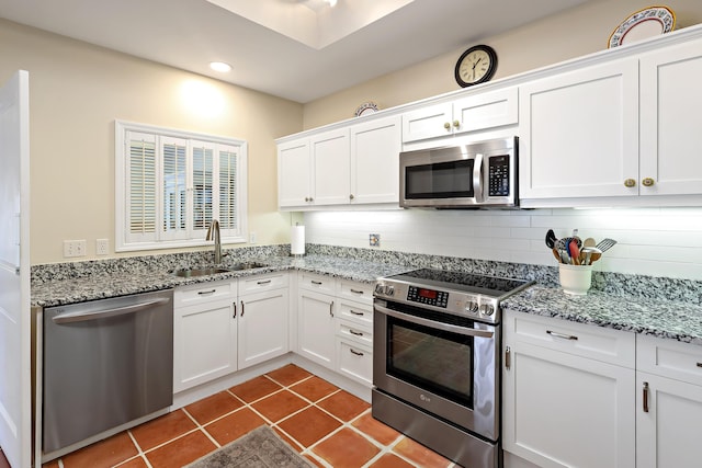 kitchen featuring stainless steel appliances, dark tile patterned flooring, sink, and white cabinets