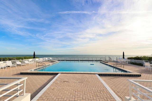 view of swimming pool featuring a patio and a water view