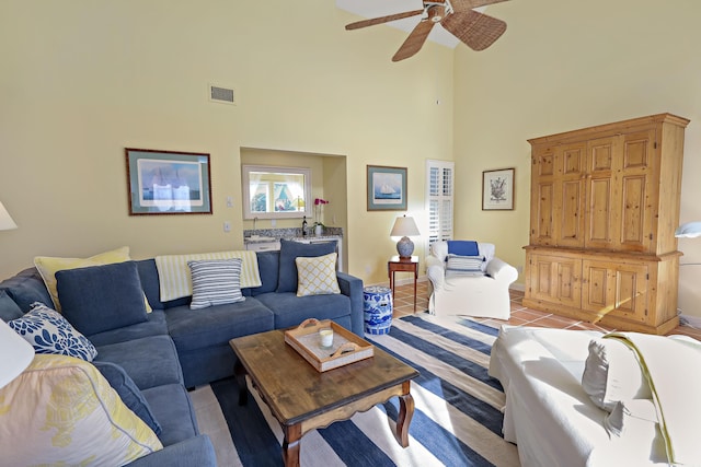 living room featuring light tile patterned floors, ceiling fan, and a high ceiling