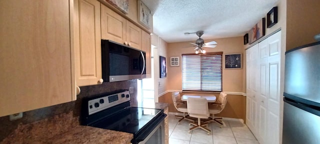 kitchen featuring ceiling fan, appliances with stainless steel finishes, a textured ceiling, and light tile patterned floors