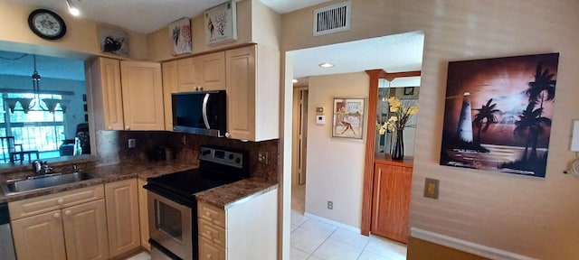 kitchen with sink, light tile patterned floors, appliances with stainless steel finishes, an inviting chandelier, and decorative backsplash