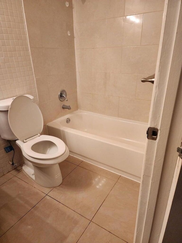 bathroom with tile patterned flooring, tiled shower / bath combo, and toilet