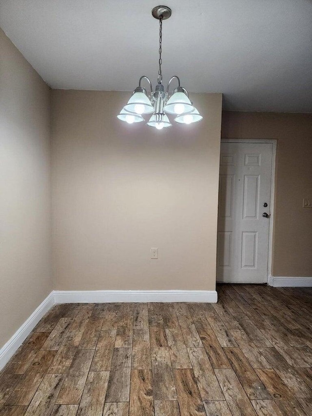 unfurnished dining area featuring an inviting chandelier and dark hardwood / wood-style flooring