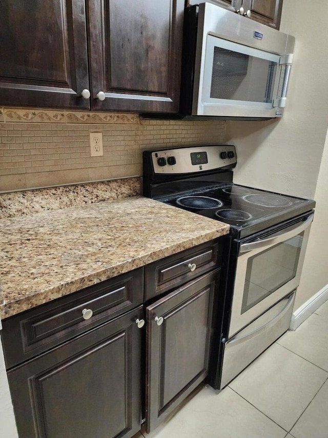 kitchen with light tile patterned flooring, decorative backsplash, light stone counters, stainless steel appliances, and dark brown cabinets